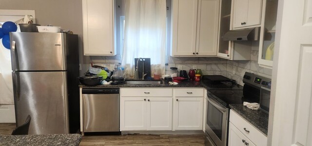 kitchen featuring dark stone counters, white cabinetry, stainless steel appliances, sink, and hardwood / wood-style flooring