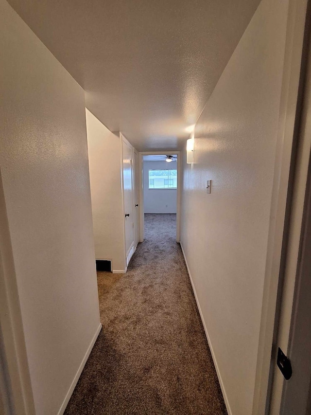 corridor featuring a textured ceiling and carpet floors