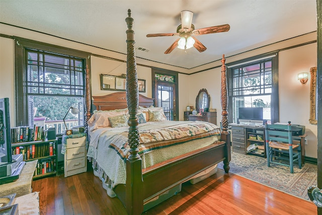 bedroom featuring dark hardwood / wood-style flooring, ceiling fan, and multiple windows