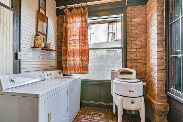 washroom featuring washing machine and dryer, wooden walls, and dark hardwood / wood-style flooring