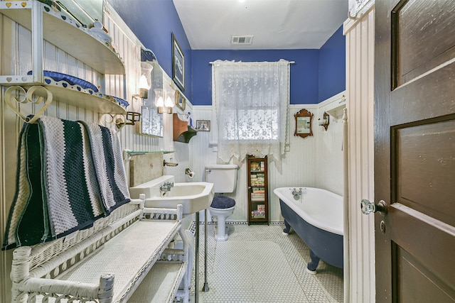 bathroom featuring tile patterned flooring, toilet, and a washtub