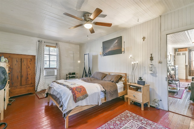 bedroom with ceiling fan, wooden walls, and dark hardwood / wood-style flooring