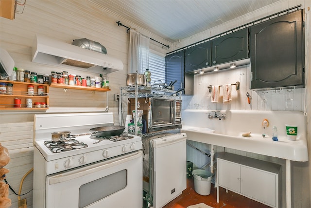 kitchen with white gas range and wood walls