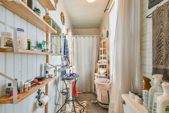 bathroom with a shower with curtain and wooden walls