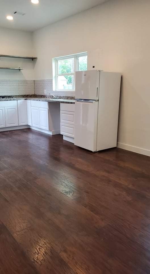 kitchen featuring white refrigerator, dark hardwood / wood-style flooring, tasteful backsplash, and white cabinets