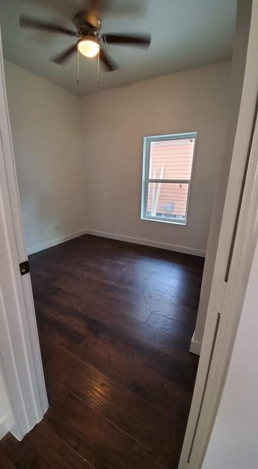 empty room with ceiling fan and dark hardwood / wood-style floors