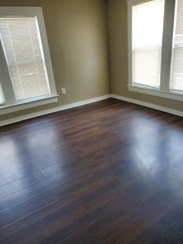 spare room featuring dark hardwood / wood-style flooring and a wealth of natural light