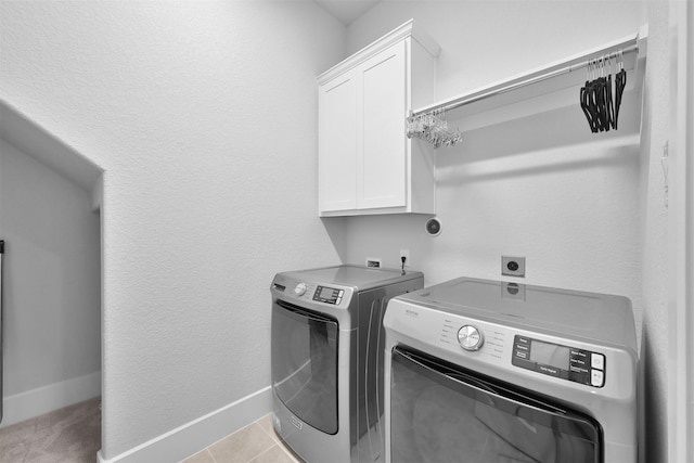 laundry room with light tile patterned floors, washing machine and clothes dryer, cabinet space, and baseboards