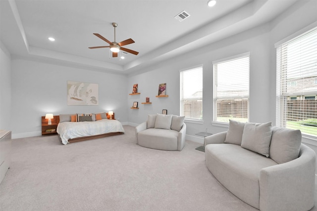 bedroom with visible vents, multiple windows, a tray ceiling, and baseboards