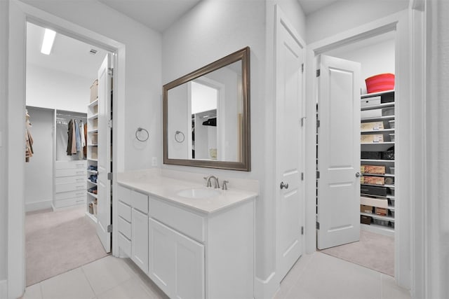 bathroom with tile patterned flooring, a spacious closet, and vanity