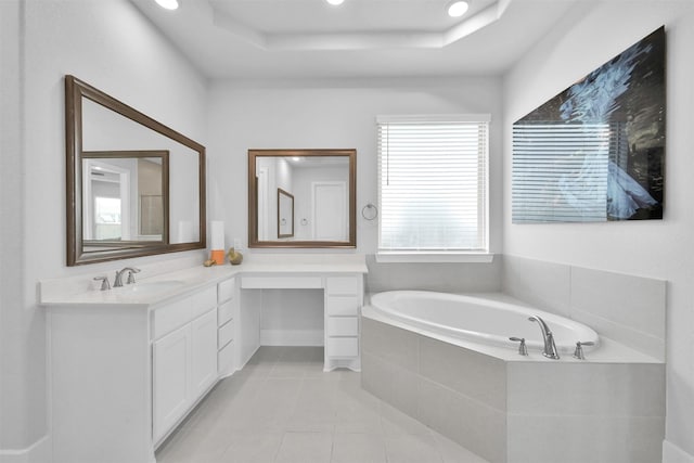 full bath featuring a garden tub, a raised ceiling, vanity, and tile patterned floors