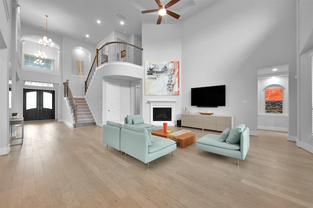 living area with light wood-type flooring, a fireplace, stairway, and baseboards