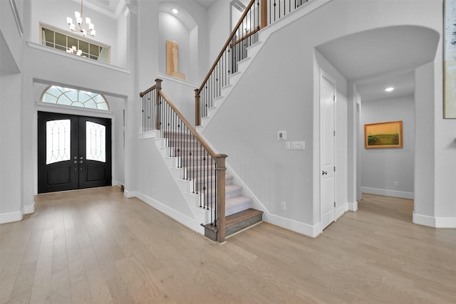 entrance foyer featuring french doors, stairway, wood finished floors, a chandelier, and baseboards