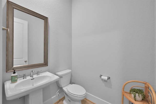 bathroom featuring a sink, toilet, and baseboards