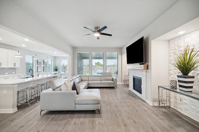 living room with a healthy amount of sunlight, ceiling fan, sink, and light hardwood / wood-style floors