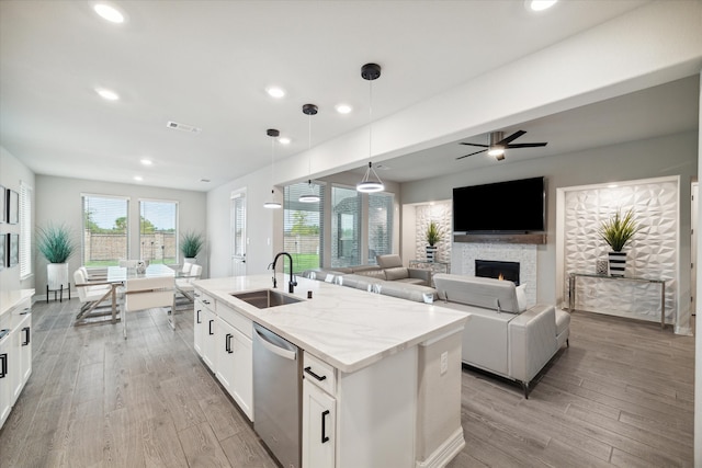 kitchen featuring a fireplace, dishwasher, sink, ceiling fan, and white cabinets