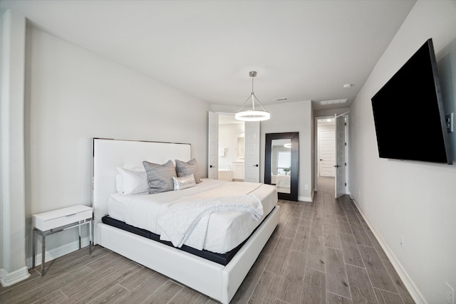 bedroom featuring ensuite bath and hardwood / wood-style floors