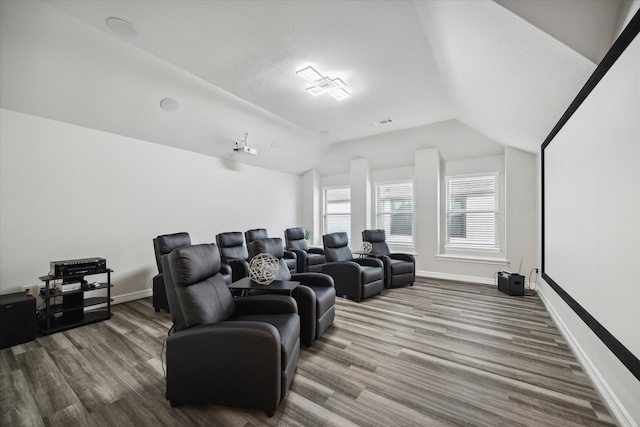 cinema room featuring hardwood / wood-style flooring, a textured ceiling, and vaulted ceiling