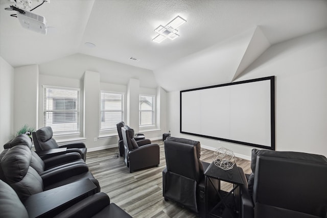 home theater room with vaulted ceiling, a textured ceiling, and wood-type flooring