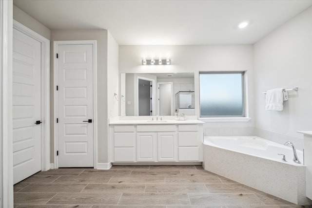 bathroom featuring vanity, tiled bath, and hardwood / wood-style flooring