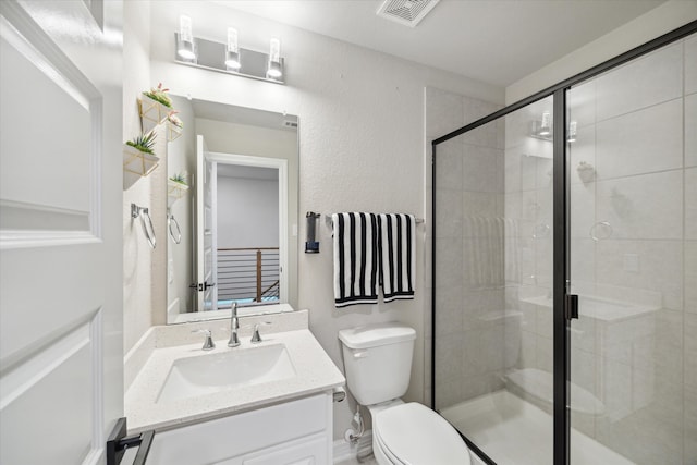 bathroom featuring a shower with shower door, toilet, and vanity