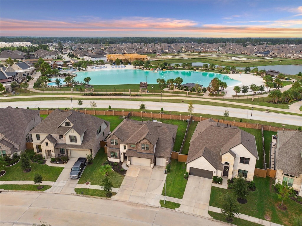 aerial view at dusk with a water view and a residential view