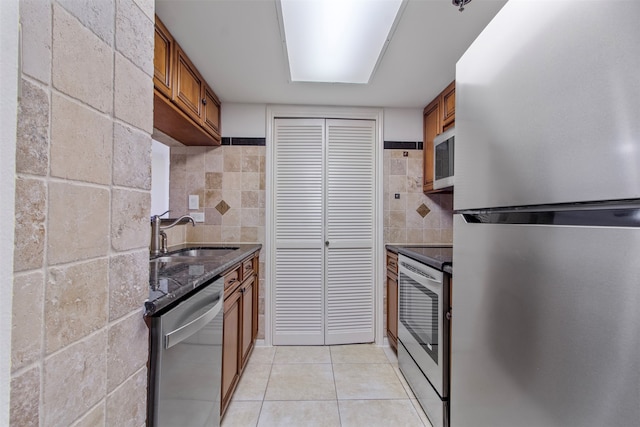 kitchen featuring appliances with stainless steel finishes, decorative backsplash, sink, and light tile patterned floors