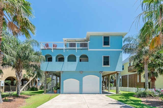 22921 Chiquita St, Galveston, TX 77554 - raised beach house with a balcony, fence, an attached garage, a front lawn, and concrete driveway
