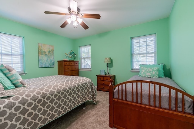 carpeted bedroom featuring multiple windows and ceiling fan