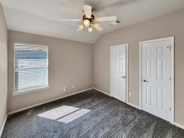 unfurnished bedroom featuring dark carpet, two closets, and ceiling fan