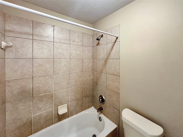 bathroom featuring tiled shower / bath combo, toilet, and a textured ceiling