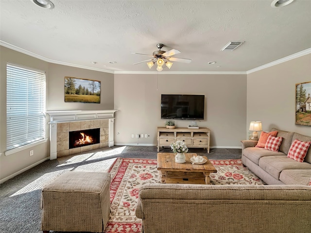 living room with ornamental molding, carpet flooring, ceiling fan, and a tile fireplace