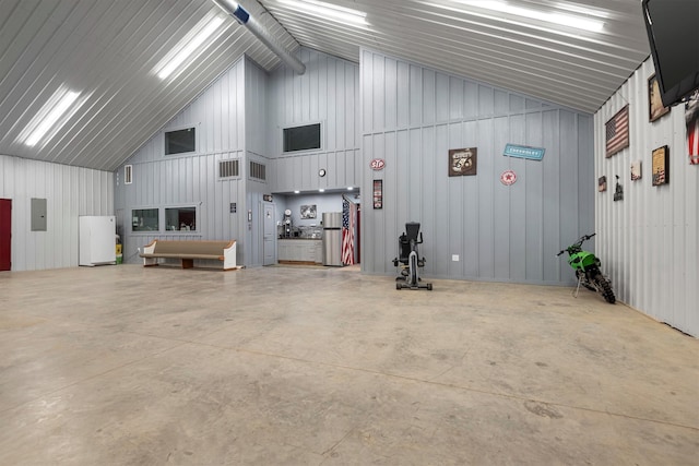 garage with white fridge, electric panel, wooden walls, and stainless steel refrigerator