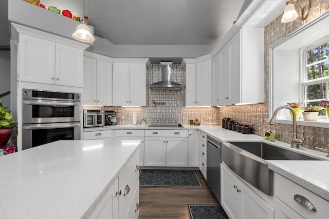 kitchen featuring white cabinetry, stainless steel appliances, light stone counters, sink, and wall chimney exhaust hood