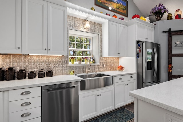 kitchen with appliances with stainless steel finishes, vaulted ceiling, sink, and white cabinets