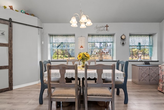 dining room with a barn door, wood-type flooring, and an inviting chandelier