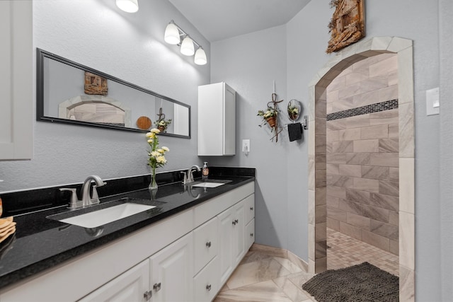 bathroom with tiled shower and vanity