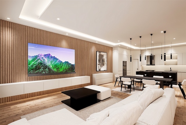 living room featuring light hardwood / wood-style flooring, a tray ceiling, and sink