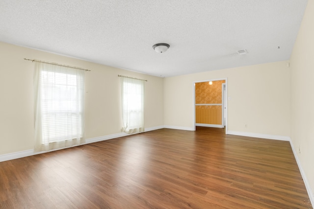 empty room featuring a textured ceiling and dark hardwood / wood-style floors