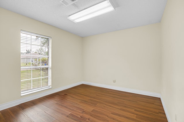 spare room featuring a textured ceiling and dark hardwood / wood-style flooring