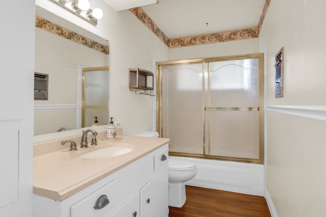 full bathroom with vanity, toilet, hardwood / wood-style floors, and bath / shower combo with glass door