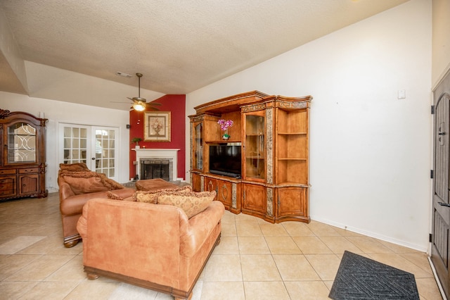 tiled living room with lofted ceiling, ceiling fan, french doors, and a textured ceiling