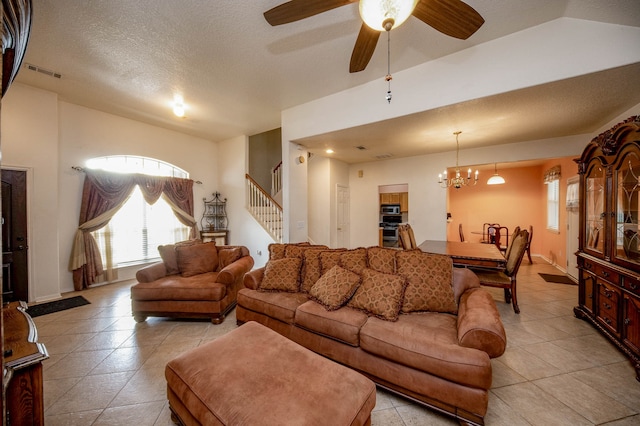 living room with ceiling fan with notable chandelier, vaulted ceiling, and a textured ceiling