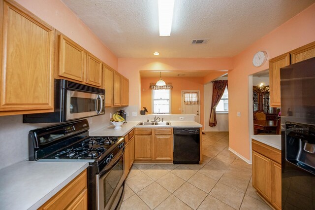 kitchen featuring a textured ceiling, black appliances, pendant lighting, light tile patterned floors, and sink