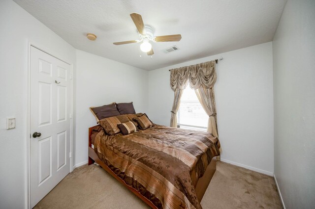 carpeted bedroom featuring a textured ceiling and ceiling fan