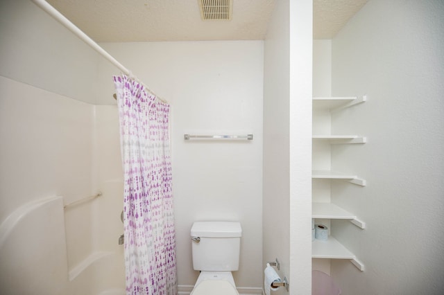 bathroom with toilet, curtained shower, and a textured ceiling