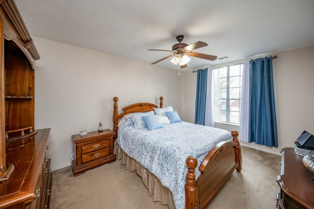 bedroom featuring ceiling fan, light colored carpet, and a textured ceiling