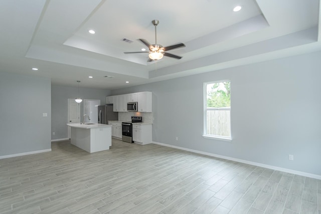 1022 Adams St, Cleveland, TX 77327 - unfurnished living room featuring a raised ceiling, a sink, ceiling fan, recessed lighting, and baseboards