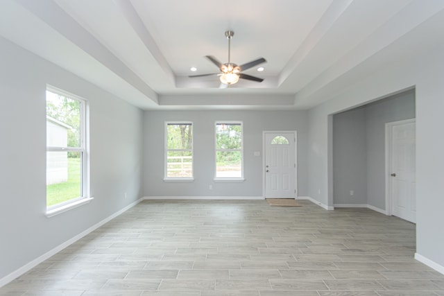 foyer featuring light hardwood / wood-style floors, a tray ceiling, and ceiling fan