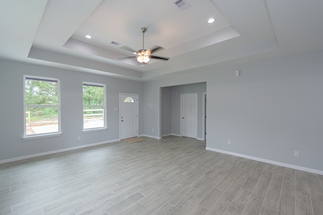 spare room with ceiling fan, light hardwood / wood-style floors, and a raised ceiling